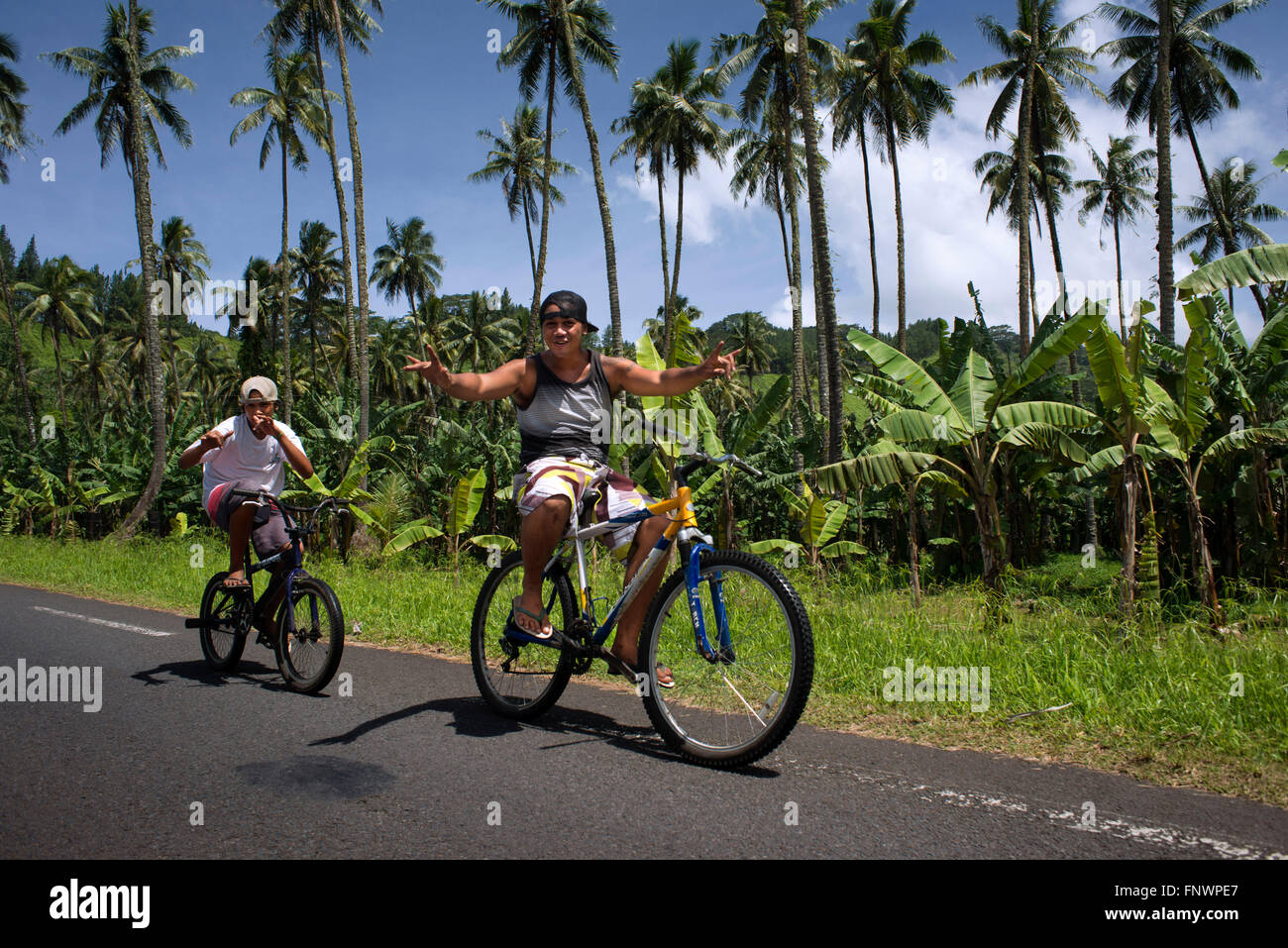 Palmen Sie und Teen jungen Radfahrer an der Route de Ceinture, Tahiti Nui, Gesellschaftsinseln, Französisch-Polynesien, Südsee. Stockfoto