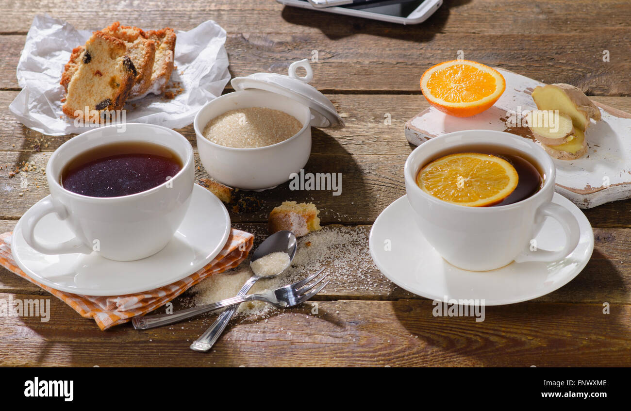 Tassen Tee mit süßen Kuchen und Orange. Stockfoto