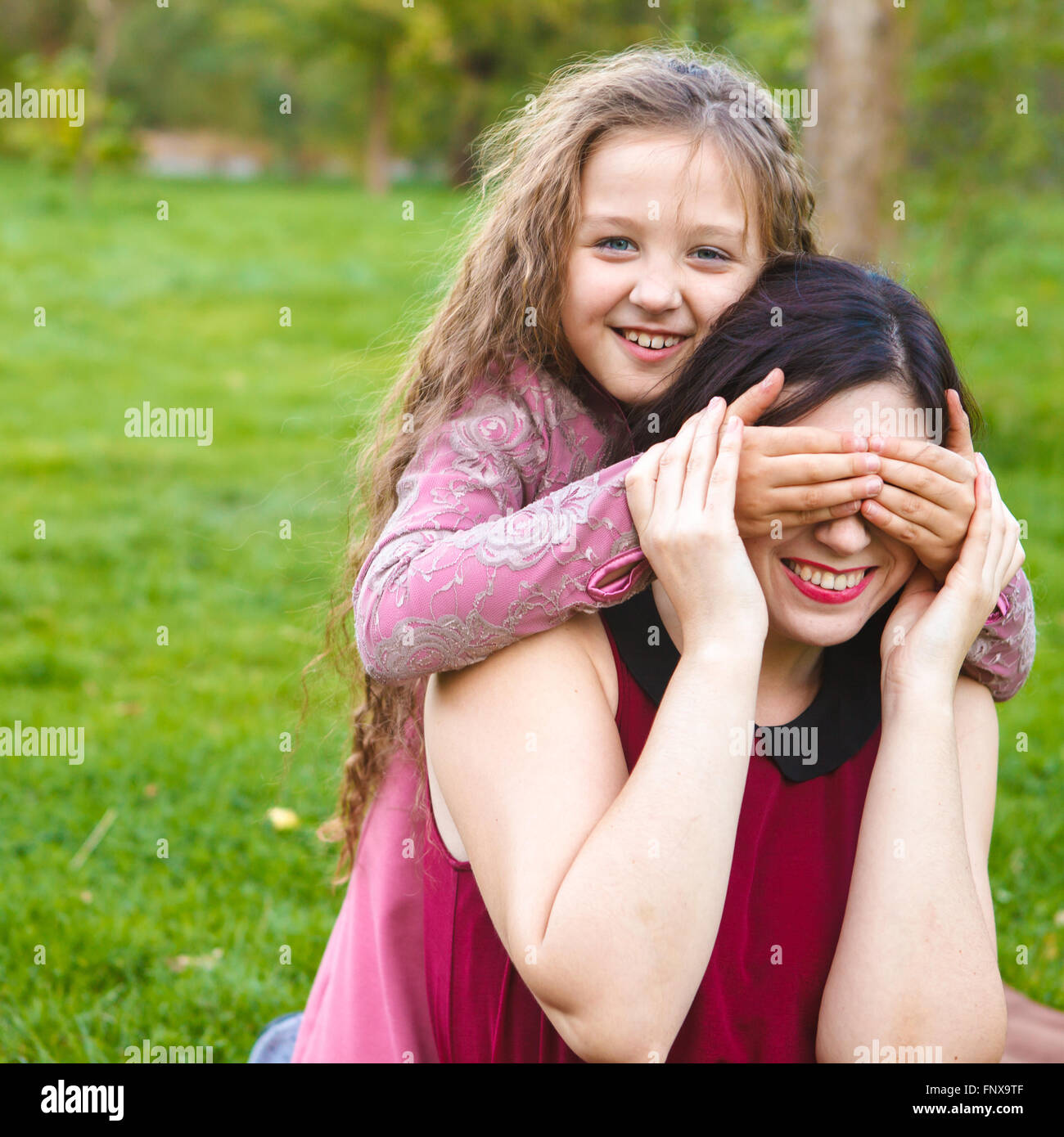 Tochter Mutter Schloß sie die Augen mit den Händen im park Stockfoto
