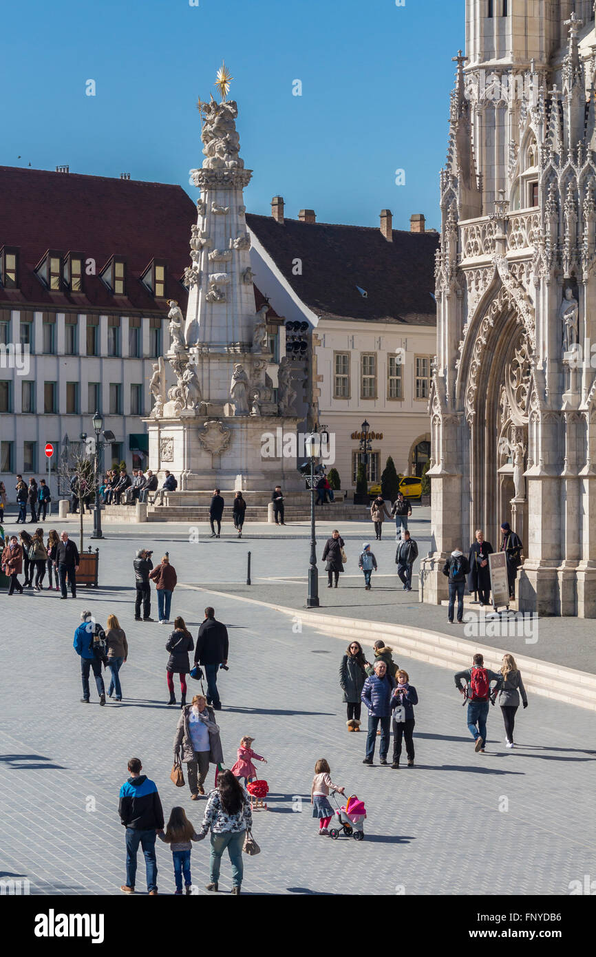 Budapest, Ungarn - 14. März 2016: Touristen auf Säule der Heiligen Dreifaltigkeit und die Matthiaskirche in Budapest, Ungarn Stockfoto