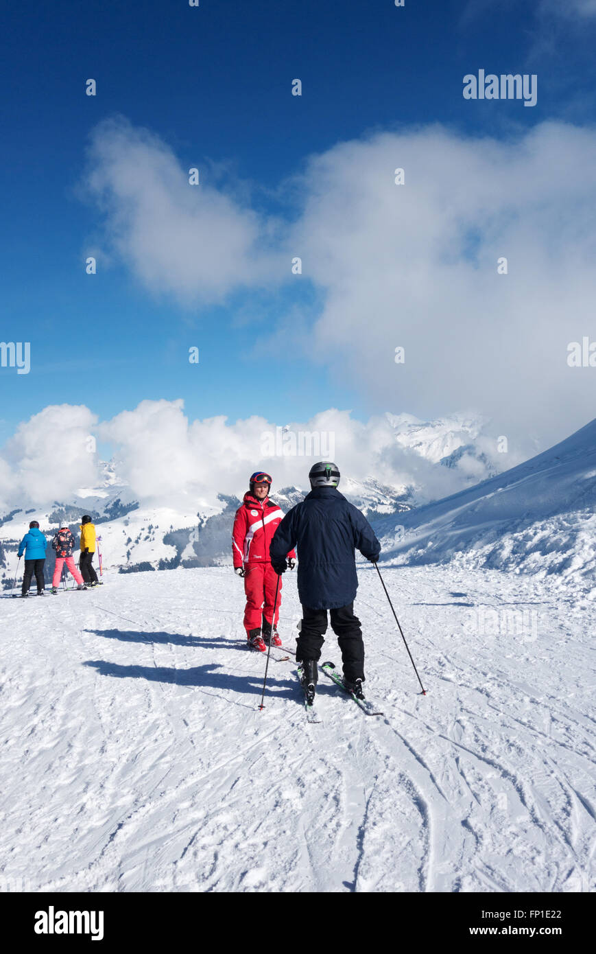 Erwachsener (in schwarz), mit einem Skikurs von einem Instruktor (in rot), die Alpen, Lenk, Kanton Bern, Schweiz, Europa Stockfoto