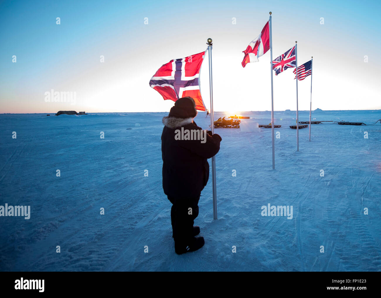 Vidar Forsmo mit Norwegian Defence Research Establishment, hisst die norwegische Flagge neben der kanadischen, britischen und US Flaggen im Ice Camp Sargo während ICEX 2016 Übung 13. März 2016 am Polarkreis. ICEX 2016 ist ein fünf-Wochen-Übung entwickelt, um Forschung, testen und bewerten die Einsatzfähigkeit in der region Stockfoto