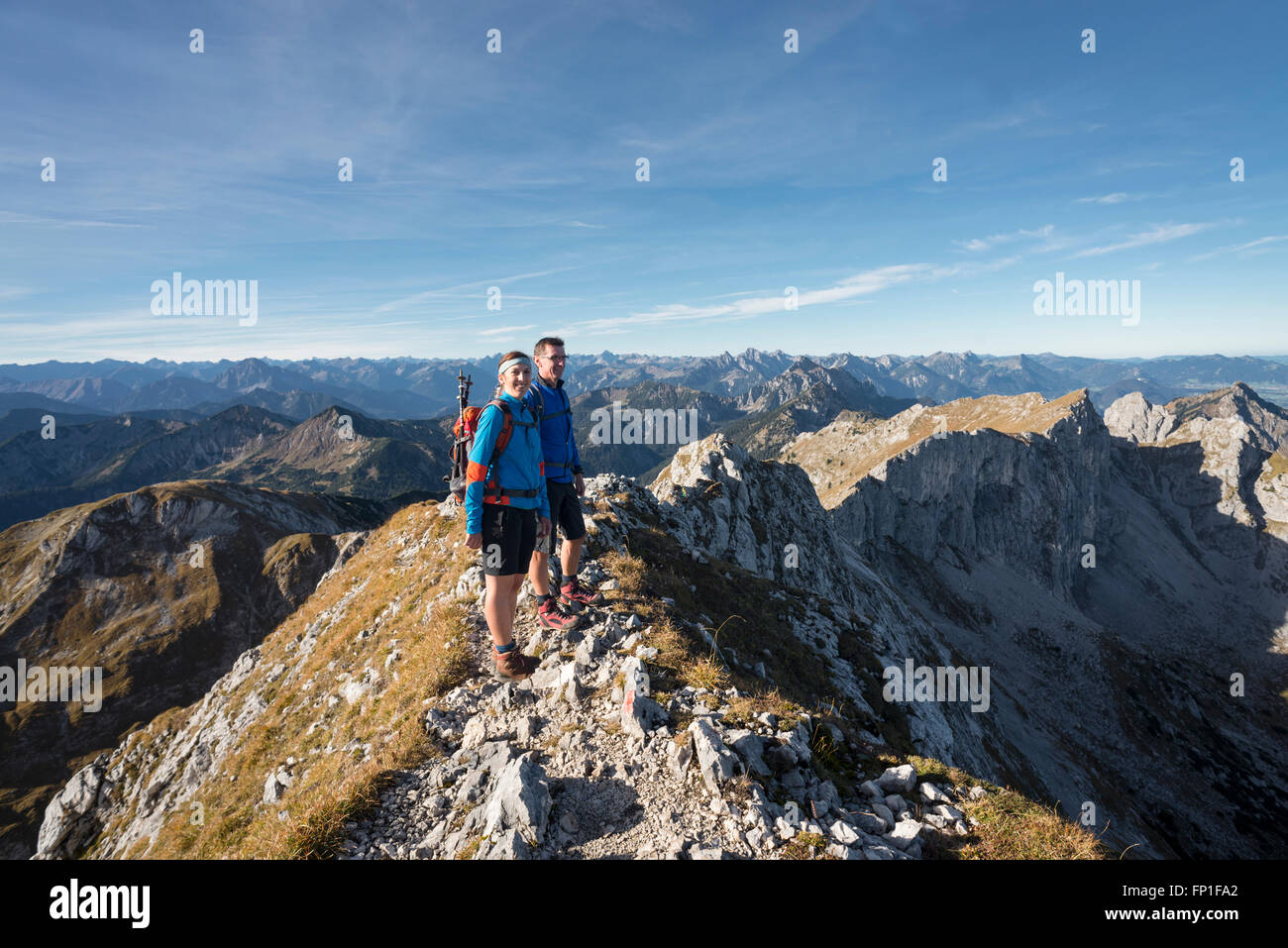 Wanderern stehen auf dem Gipfelgrat des Mount Hochplatte mit dem Panorama der Ammergauer Alpen an einem Herbstmorgen, Bayern, Deutschland Stockfoto