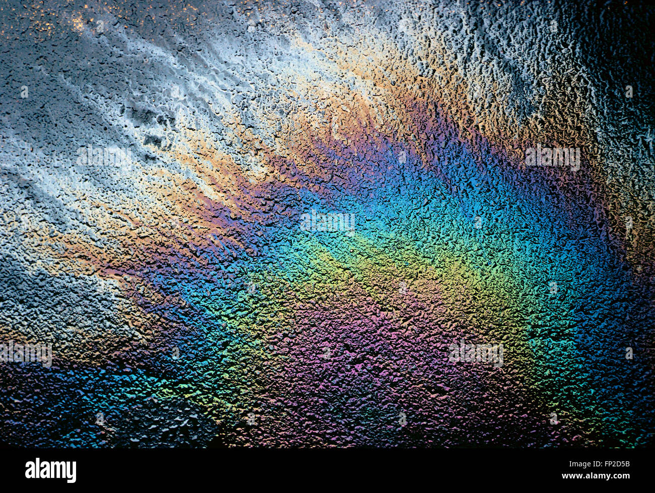 Verschüttetes Öl auf asphaltierten Parkplatz schafft Regenbogen von Farben Stockfoto