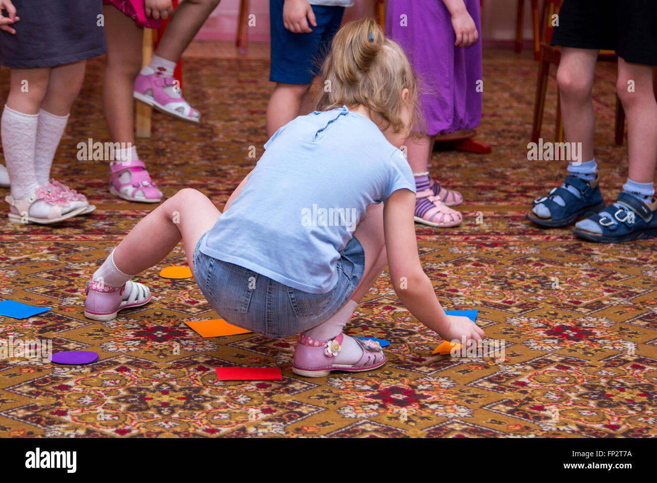 kleines Mädchen ordnet farbige Formen auf dem Teppich Stockfoto