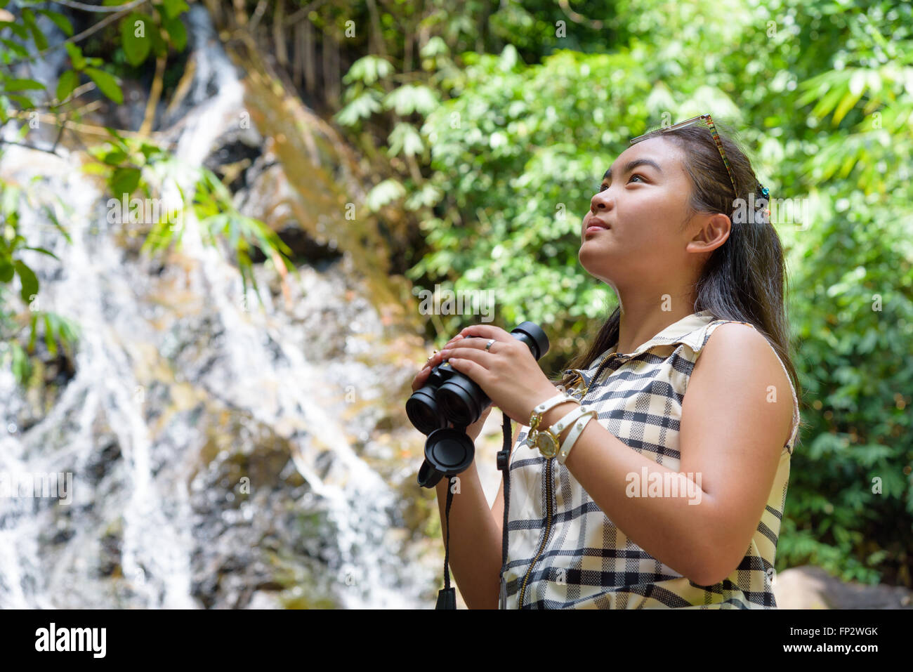 Schönes junges Mädchen Wandern nutzt Fernglas Optik für Vögel in tropischen Wald in der Nähe der Wasserfälle in Thailand Stockfoto