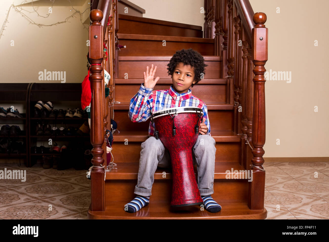 Junge mit Trommel auf Treppen. Afro junge Weihnachten Trommel Leistung. Wie etwa einige Weihnachtslieder. Moment der Improvisation. Stockfoto