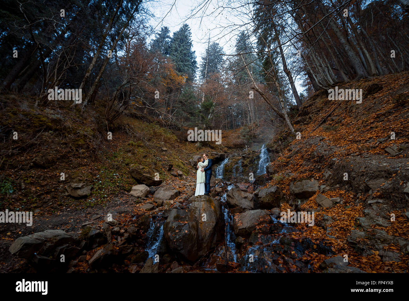 Hochzeit paar sanft umarmt auf dem Wasserfall. Nebliger Tag in Bergen Stockfoto