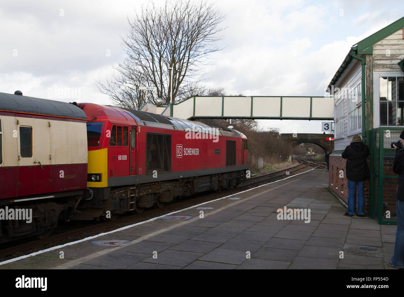 Eine DB Cargo Rail Klasse 60 Diesellok schleppt einen Personenzug der Charta durch Plattform 4 Helsby Station in Cheshire. Stockfoto