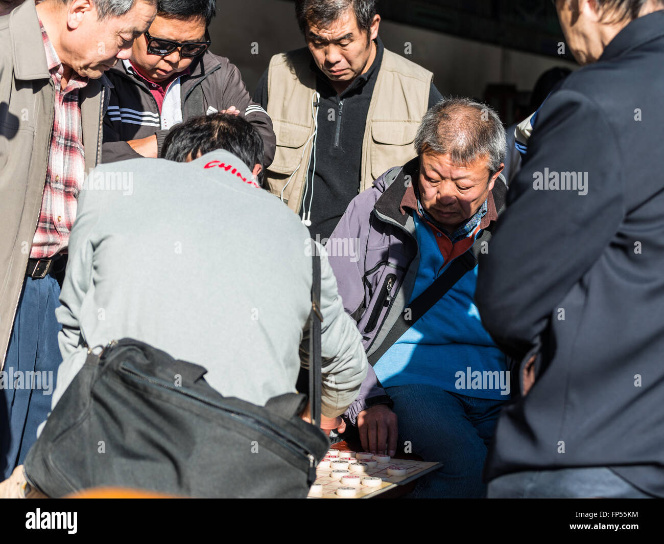 Senioren Herren ein Spiel des Xiangqi, oder chinesisches Schach, genau beobachtet von anderen in den beliebten Tempel des Himmels Park Stockfoto