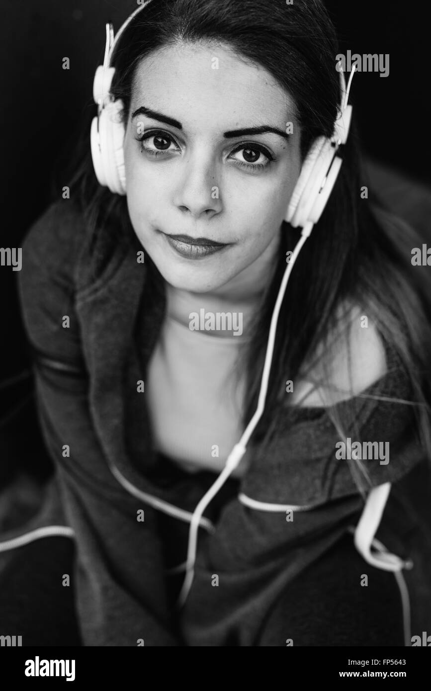 Schwarz / weiß Halblängen der jungen schönen Mischlinge Frau Musik hören mit Kopfhörern, die auf der Suche in der Kamera Lächeln - entspannend, heiter, Musikkonzept Stockfoto