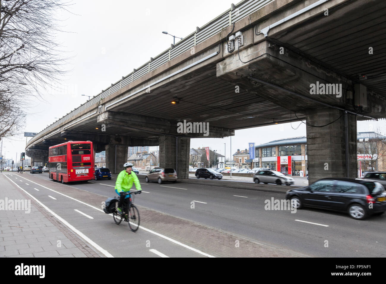 Der Verkehr auf der A4 unterwegs und ein Radfahrer auf einem Radweg mit einem Teil der erhöhten Autobahn M4 Overhead, Brentford, London, England, Großbritannien Stockfoto