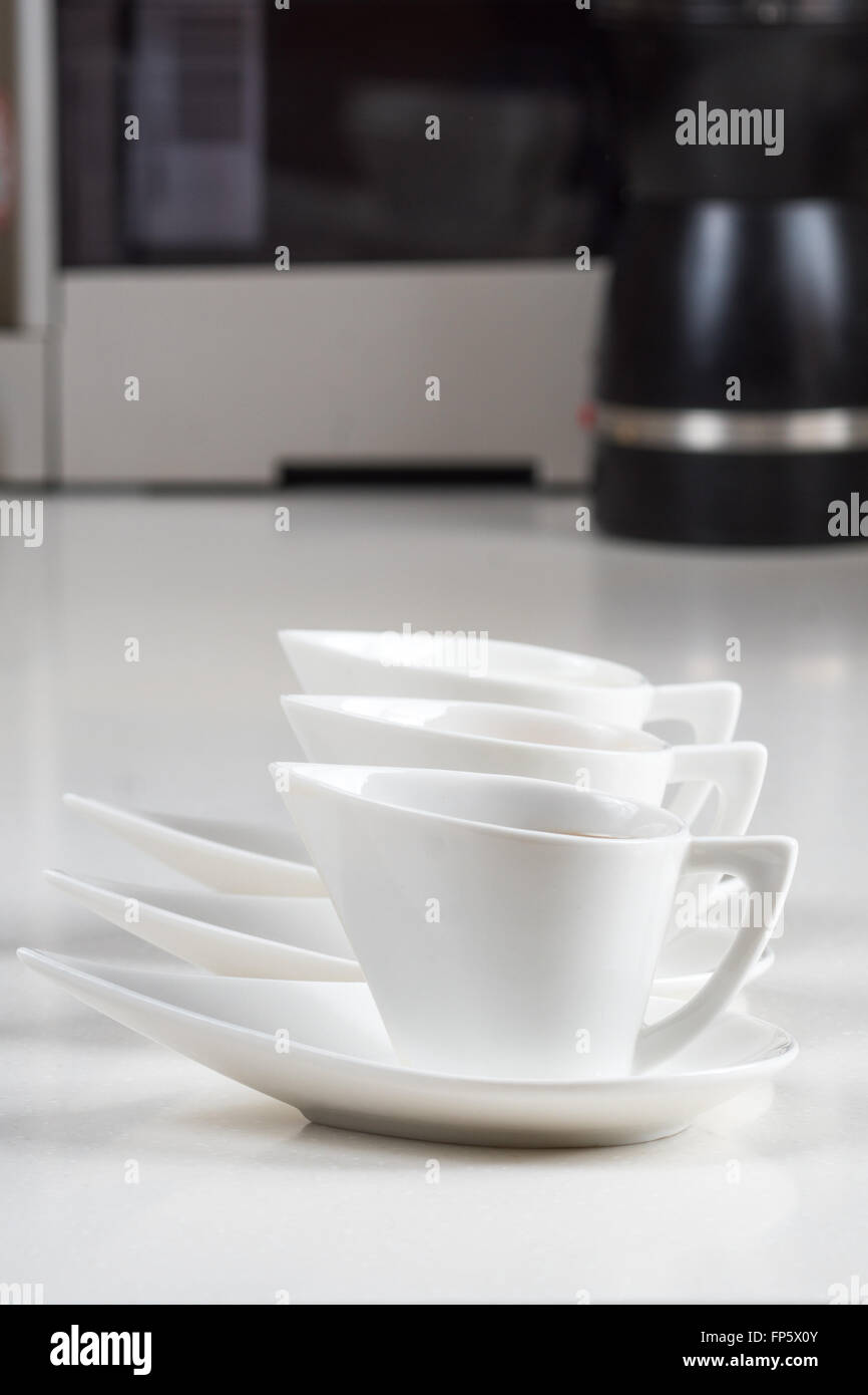 drei weiße Kaffeetassen mit Kaffee Maschine und Mühle Hintergrund Stockfoto