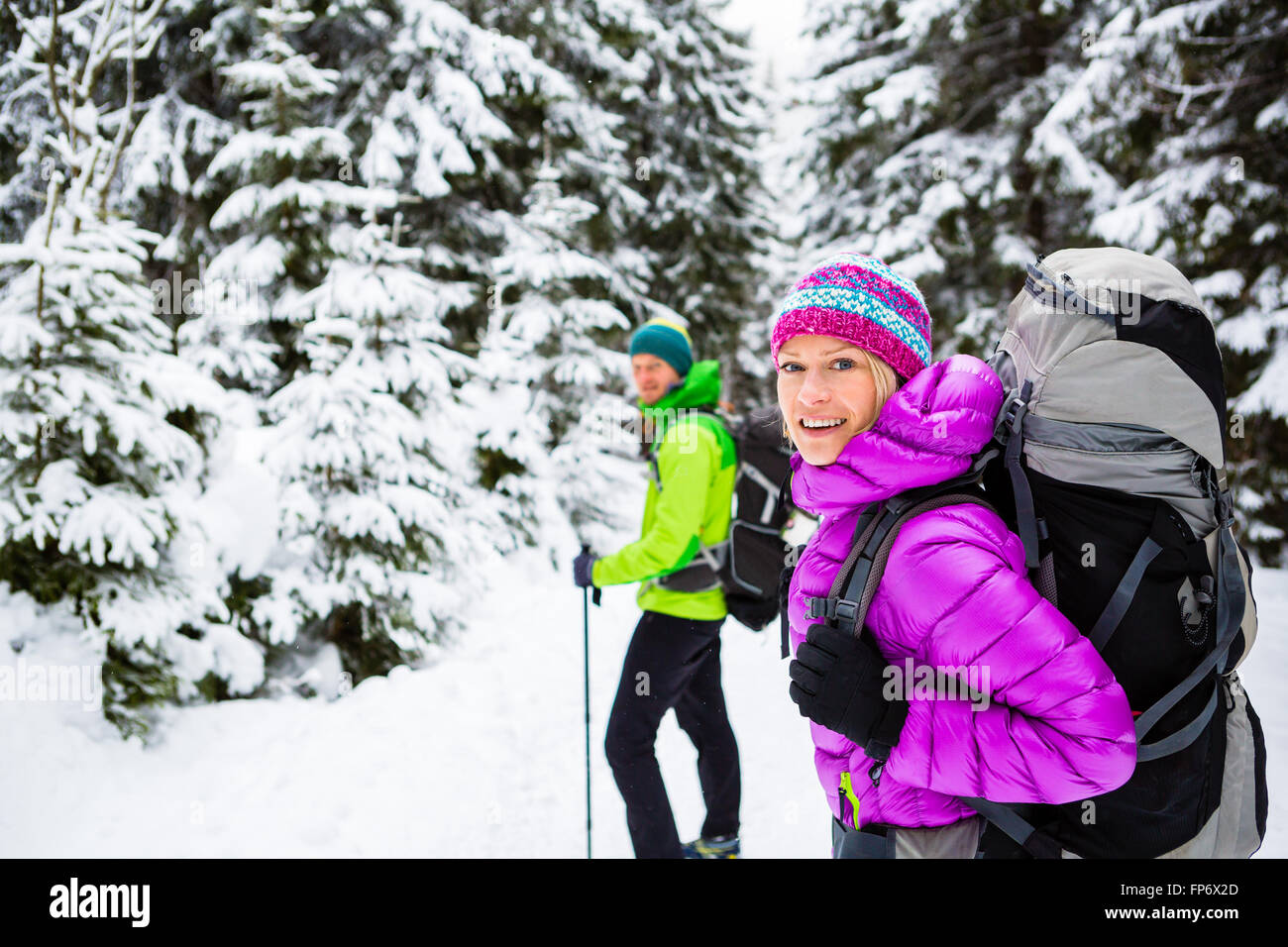 Mann und Frau glückliche Paar Wanderer, trekking im weißen Winterwald und Berge. Junge Menschen gehen auf verschneiten Trail Rucksack Stockfoto