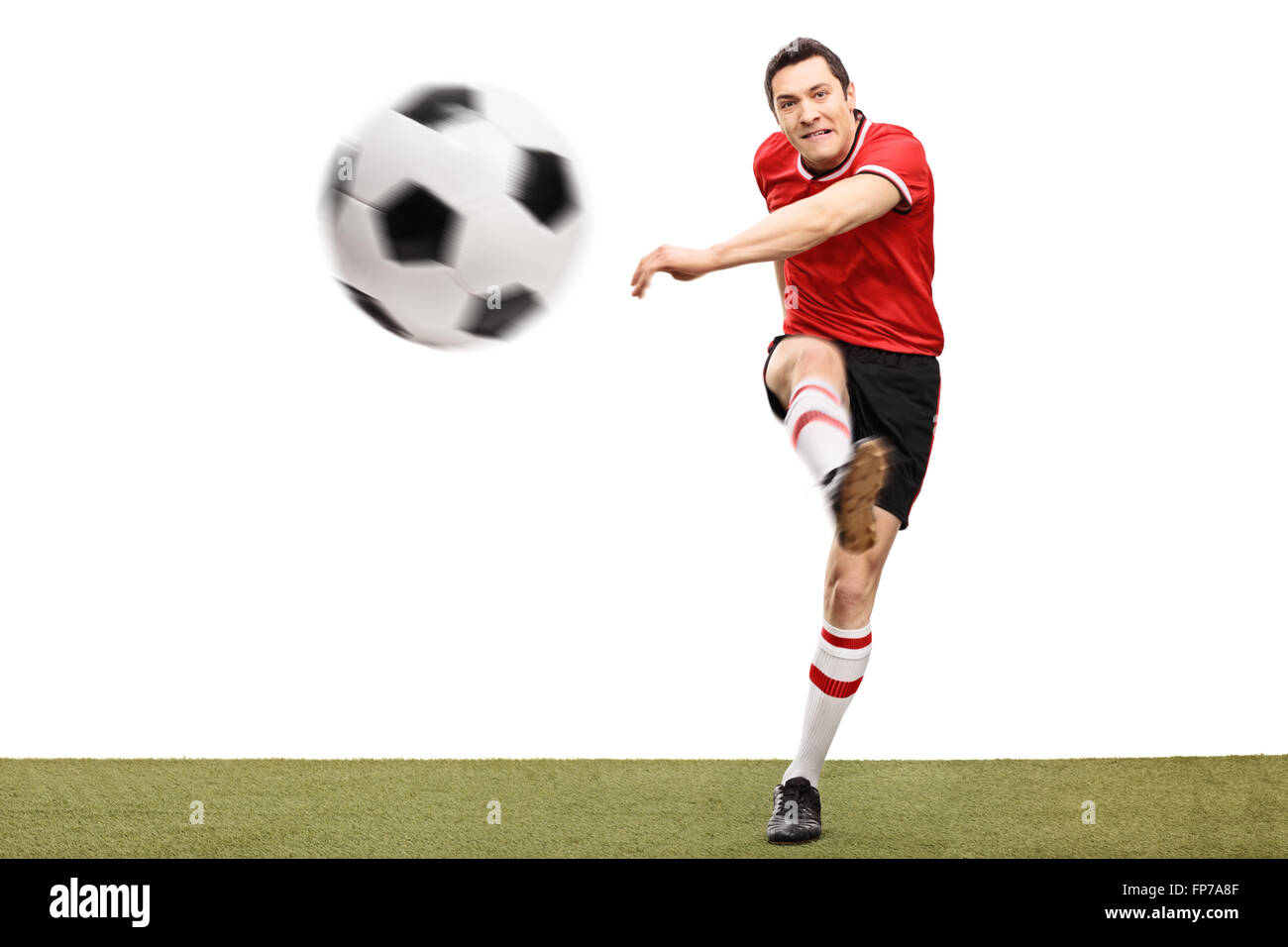 Studioaufnahme von ein junger Fußballspieler einen Ball auf einer Rasenfläche, die isoliert auf weißem Hintergrund Stockfoto