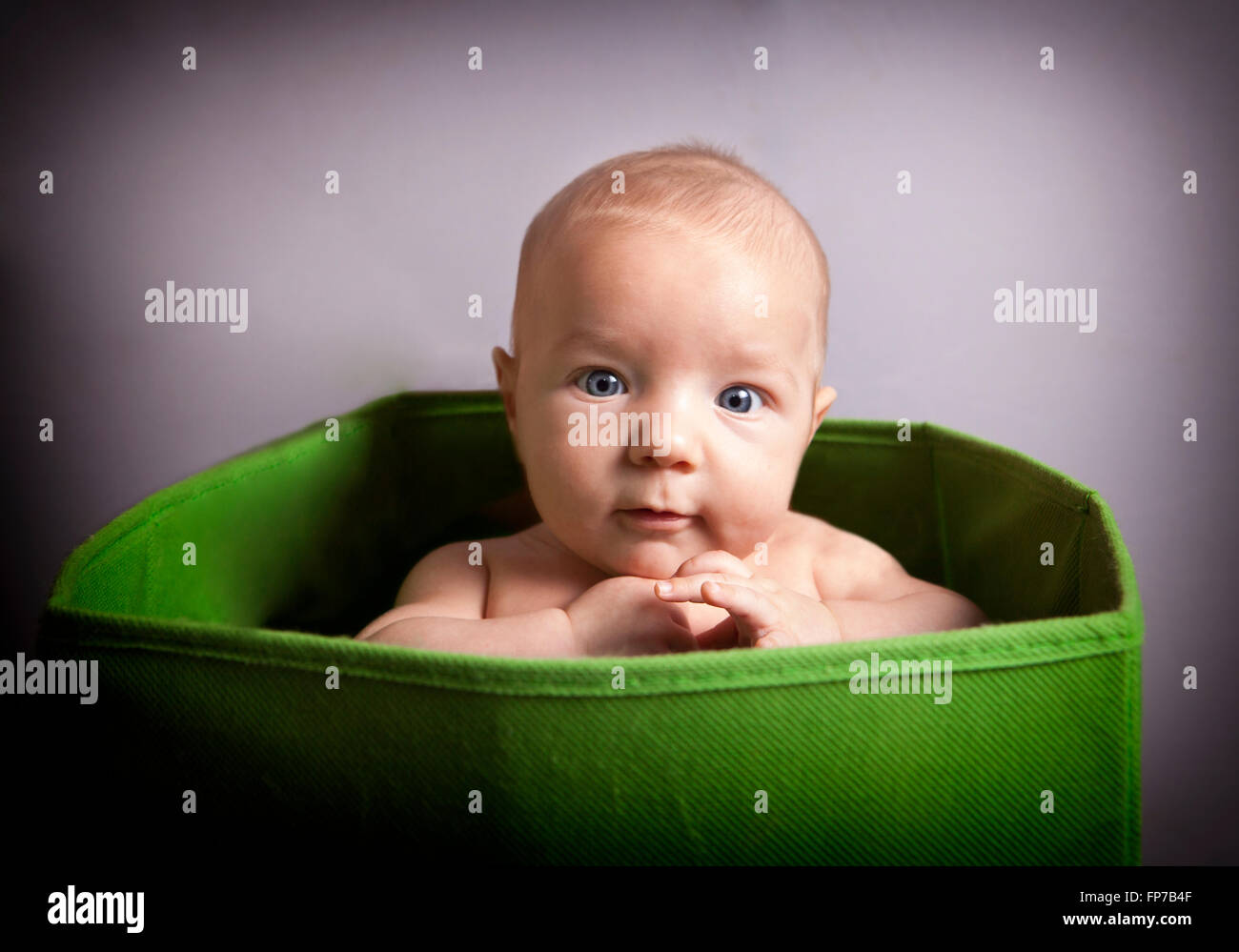 Portrait eines niedlichen 3 Monate Babyjungen sitzen in einer grünen Box für Spielzeug Stockfoto