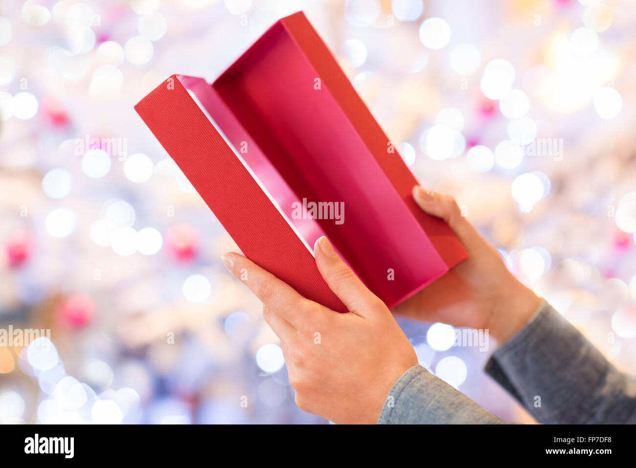Frau öffnet ein rotes Kästchen vorhanden. Boke Weihnachtsbaum hellen Hintergrund Stockfoto
