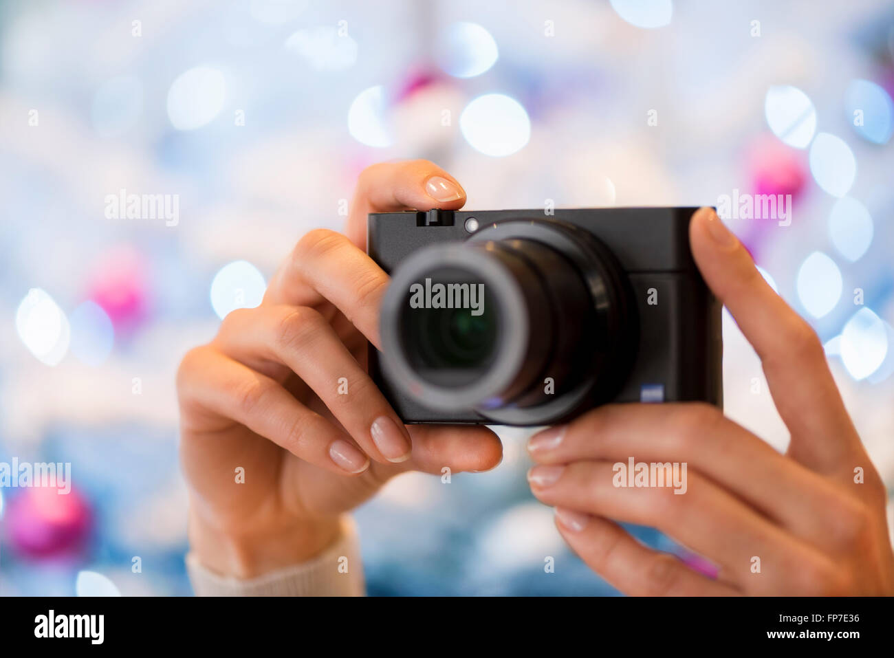 Frau nimmt ein Bild mit einem kompakten Fotoapparat vor einem Weihnachtsbaum Stockfoto