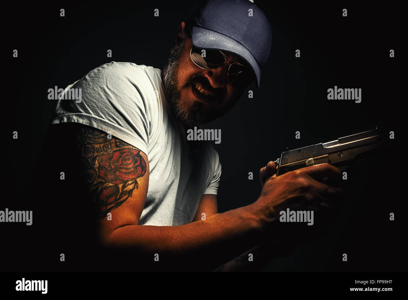 Gesichtsausdruck von einem Mann mit Gewehr und Tätowierung. Stockfoto