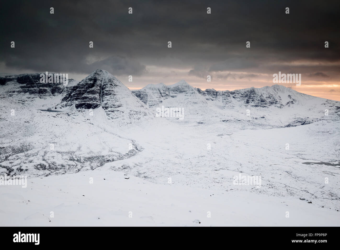 Die weite schneebedeckte Landschaft von Torridon bei Sonnenuntergang mit Beinn Eighe und Liathach als Hintergrund, vom Gipfel des Beinn A' Chearcaill Stockfoto