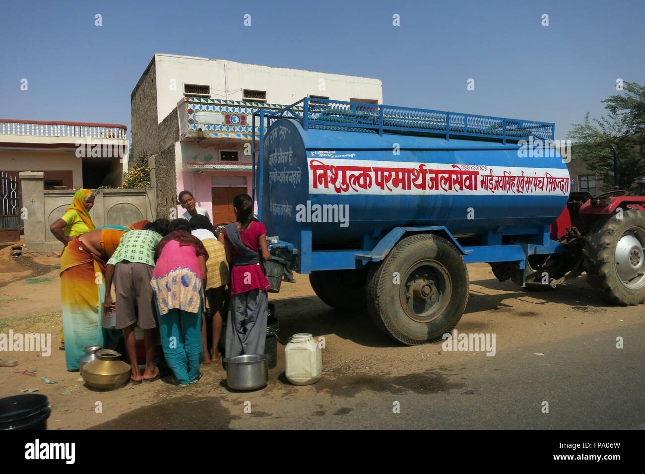 Rajasthan, Indien, versammeln sich Menschen auf einer öffentlichen Straße um eine Regierung Wasserversorgung Tanker ihre Behälter mit Wasser füllen Stockfoto