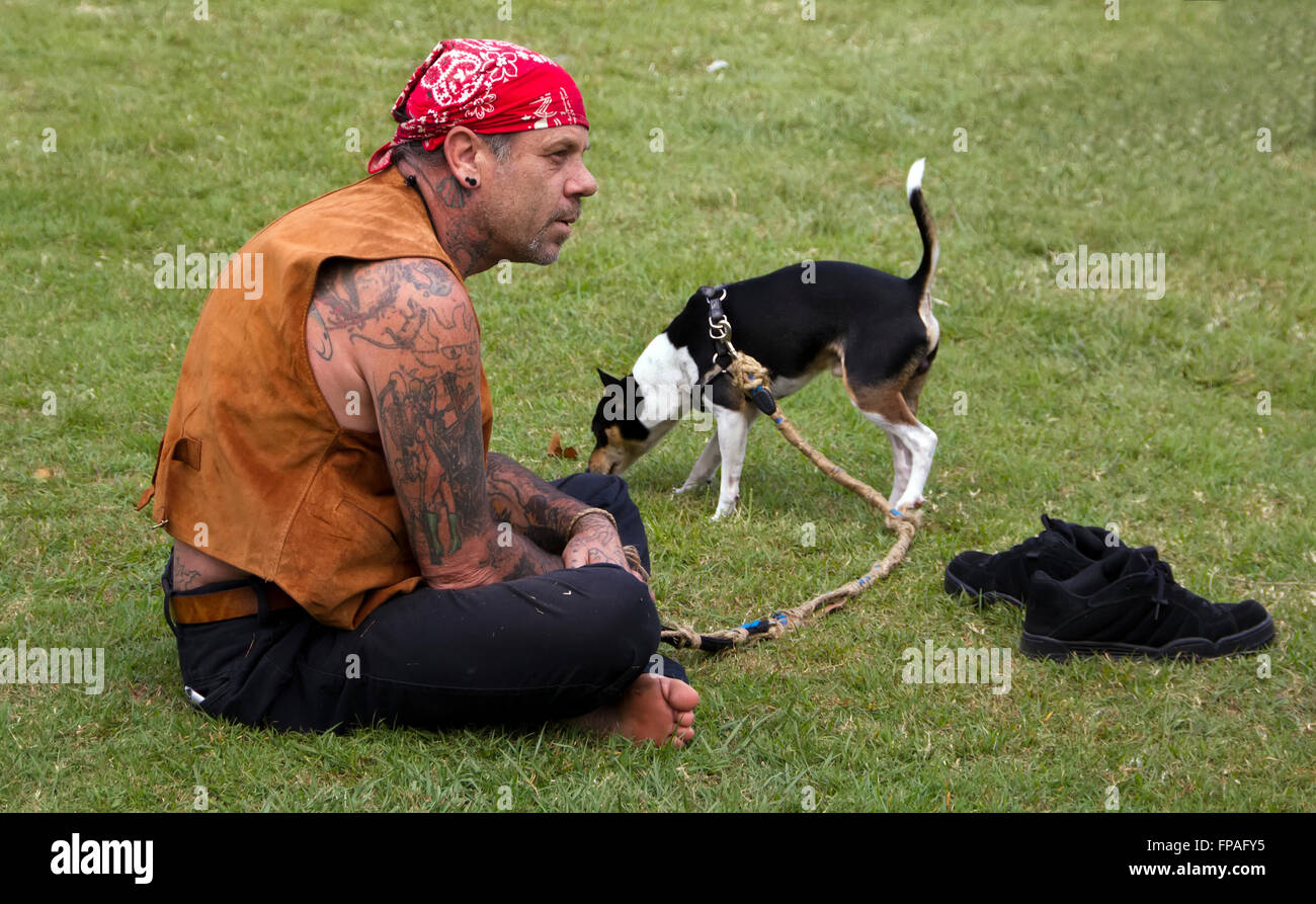 tätowierte Biker Bikie tragen Kopf Halstuch Schal und Leder Weste mit Hund Rest auf Rasen Stockfoto
