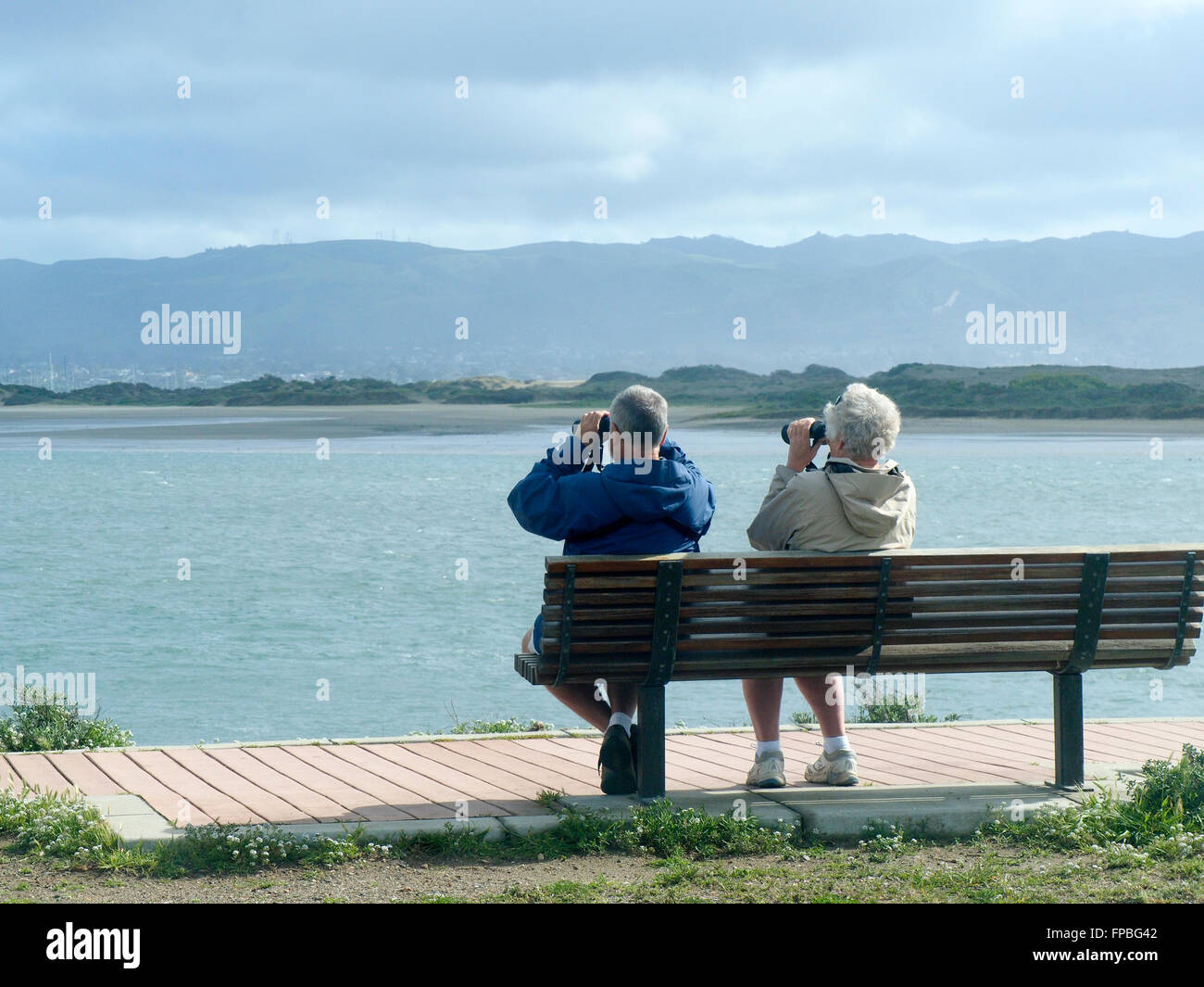 Älteres Paar am Meer, das Fernglas benutzt, um nach Wildtieren zu suchen Stockfoto