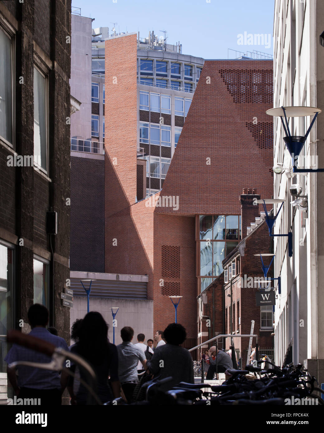 Die scharfe abgewinkelt Mauerwerk und Glas Eingang des LSE Student Centre O'Donnell & Tuomey Architekten, am unteren Rand eine schmale Gasse, die junge Menschen Fräsen darüber gesehen. Stockfoto
