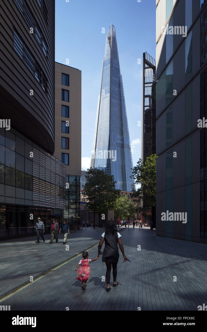 Londons höchste Gebäude The Shard Türme im Hintergrund, wie Menschen über ihr Geschäft in der von Bäumen gesäumten Fußgängerzone gehen. Stockfoto