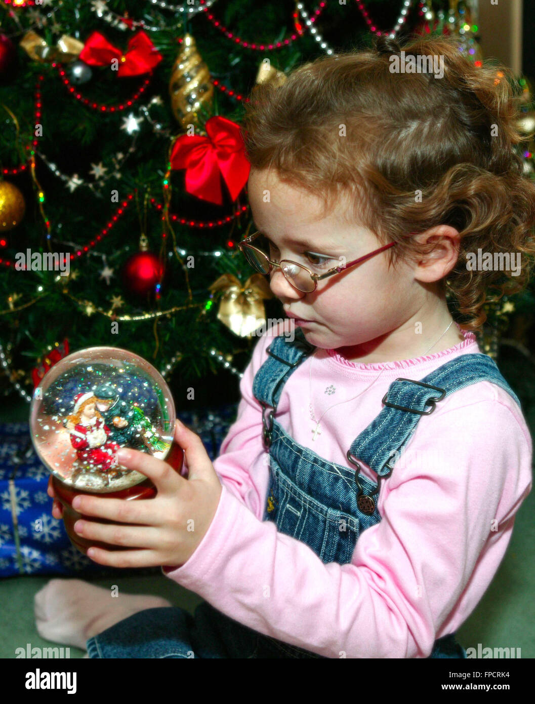 Kind sitzt unter Weihnachtsbaum Dekorationen betrachten Stockfoto
