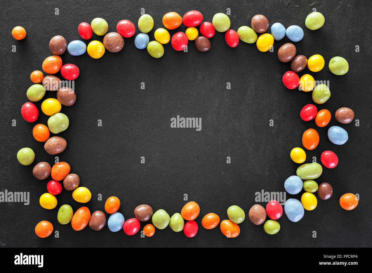 Bunte Rahmen hergestellt von Süßigkeiten in einem dunklen Stein Hintergrund, Platz für Text. Stockfoto