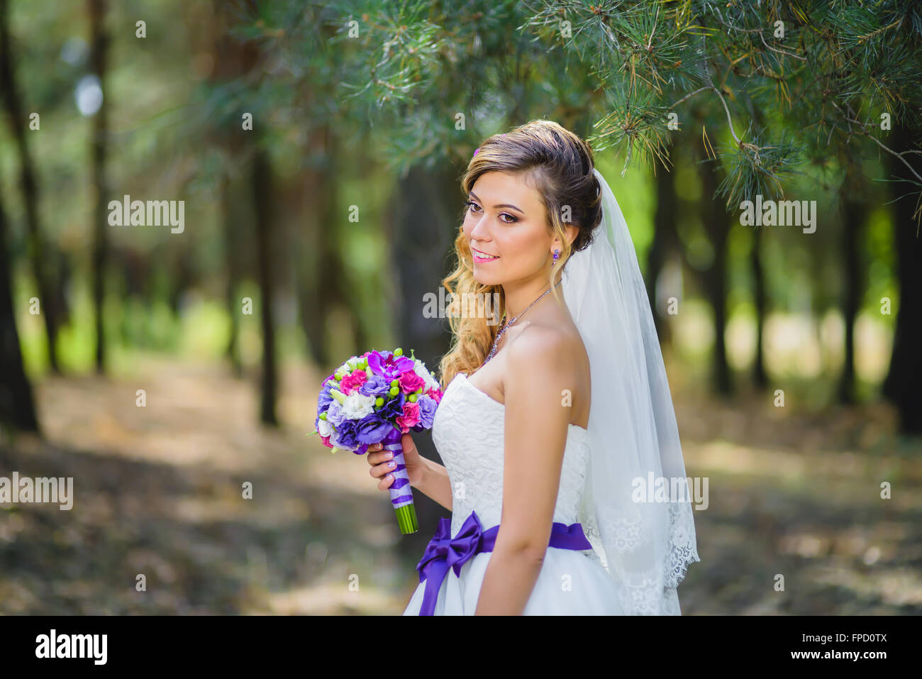 Das Mädchen in einem Brautkleid mit lila Schleife Stockfoto