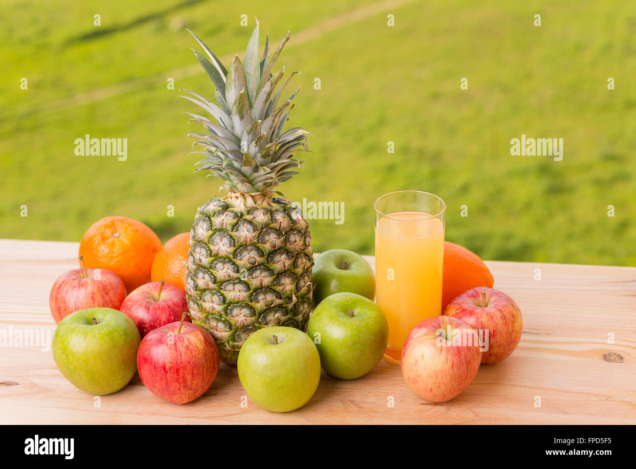 Glas Orangensaft und viele Früchte auf Holztisch im freien Stockfoto