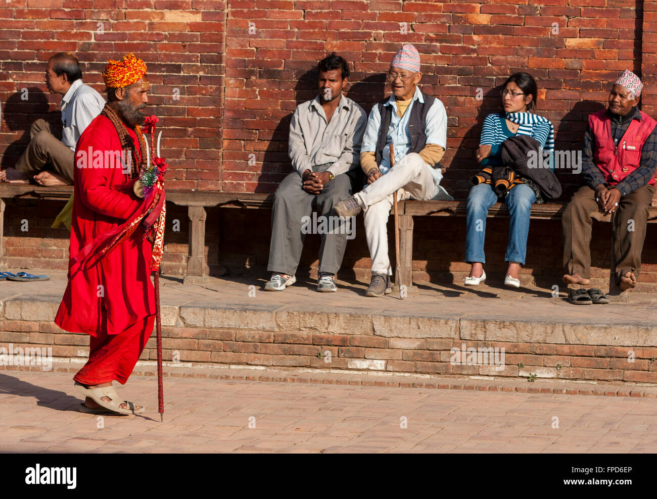 Nepal, Patan.  Ein Hindu Sadhu (Heiliger) geht es vorbei an Männer und eine Frau ruht auf Bank am Durbar Square. Stockfoto