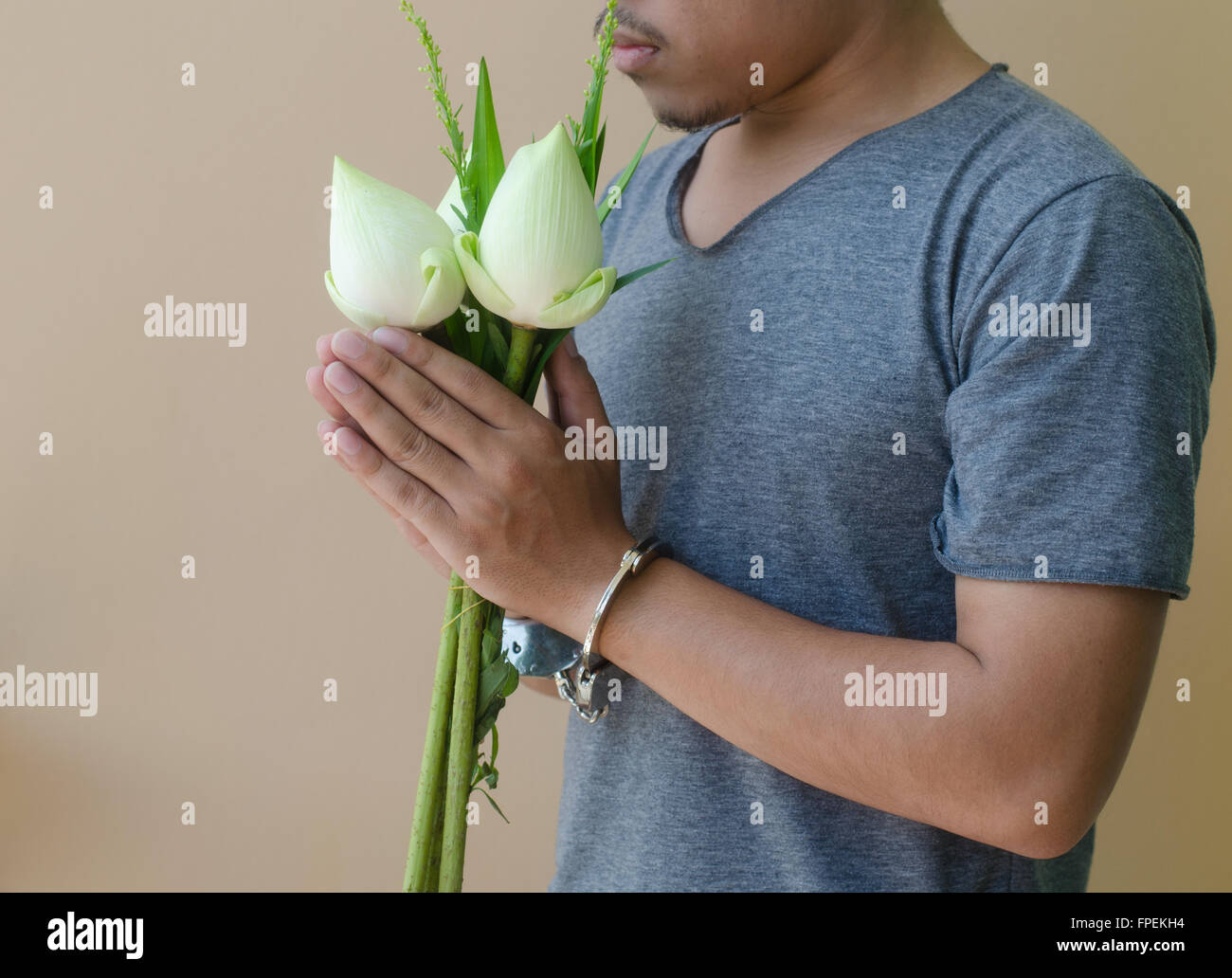 Junger Mann in Handschellen und Lotus in der hand Stockfoto