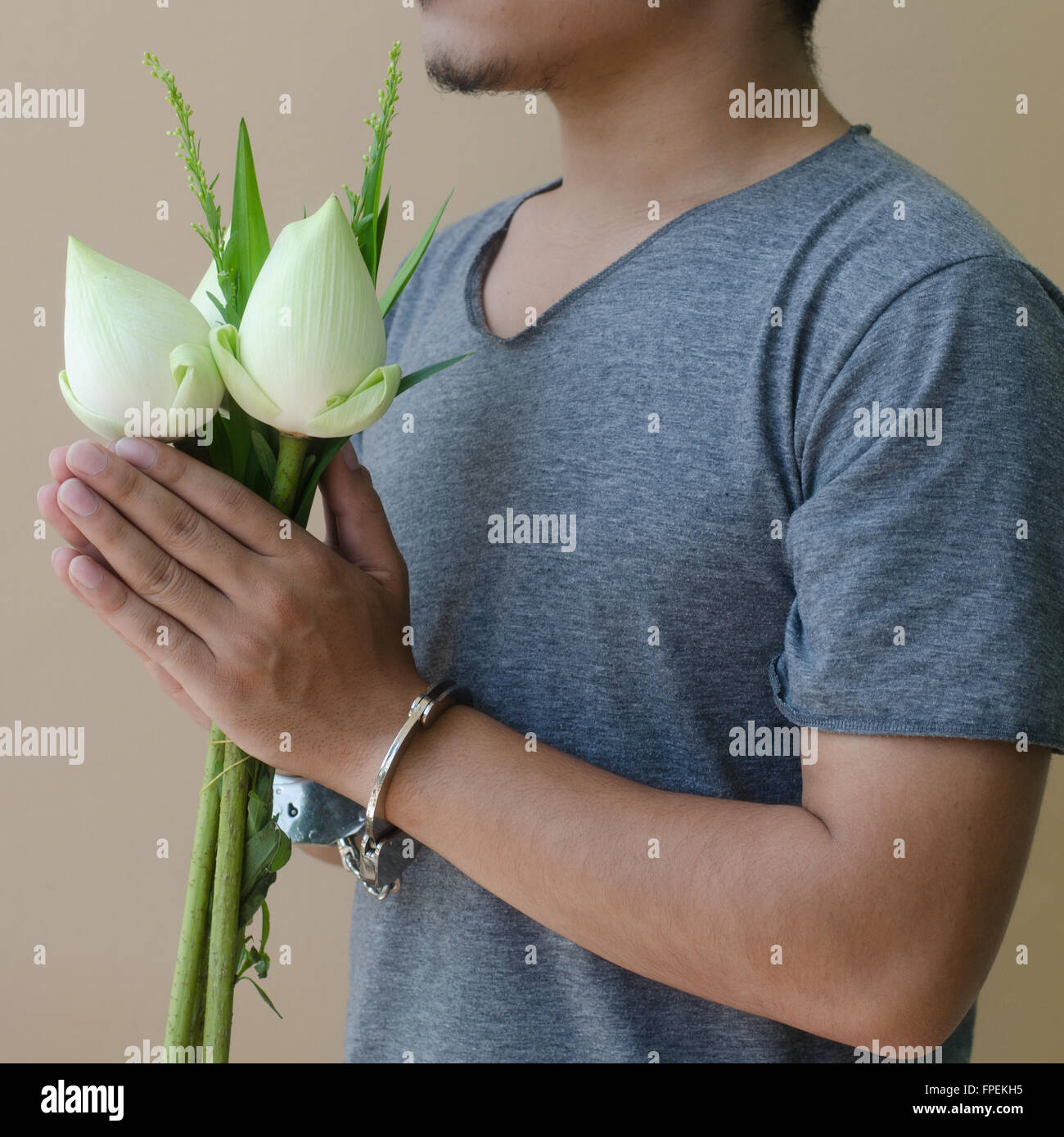 junger Mann in Handschellen und Lotus in der hand Stockfoto