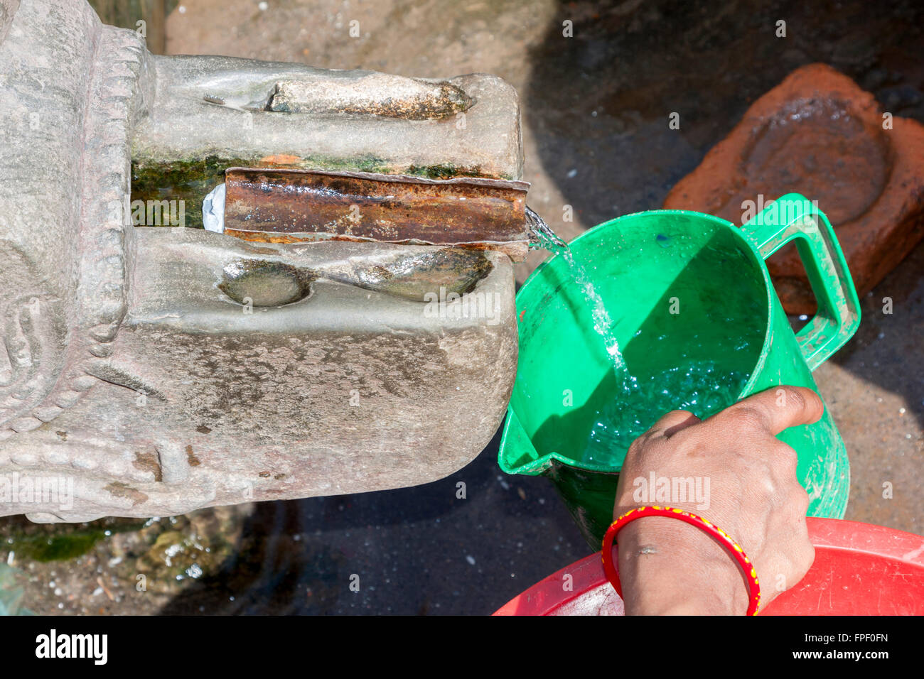 Nepal, Patan.  Frau, Füllung Kunststoff Krug an einem öffentlichen Brunnen. Stockfoto
