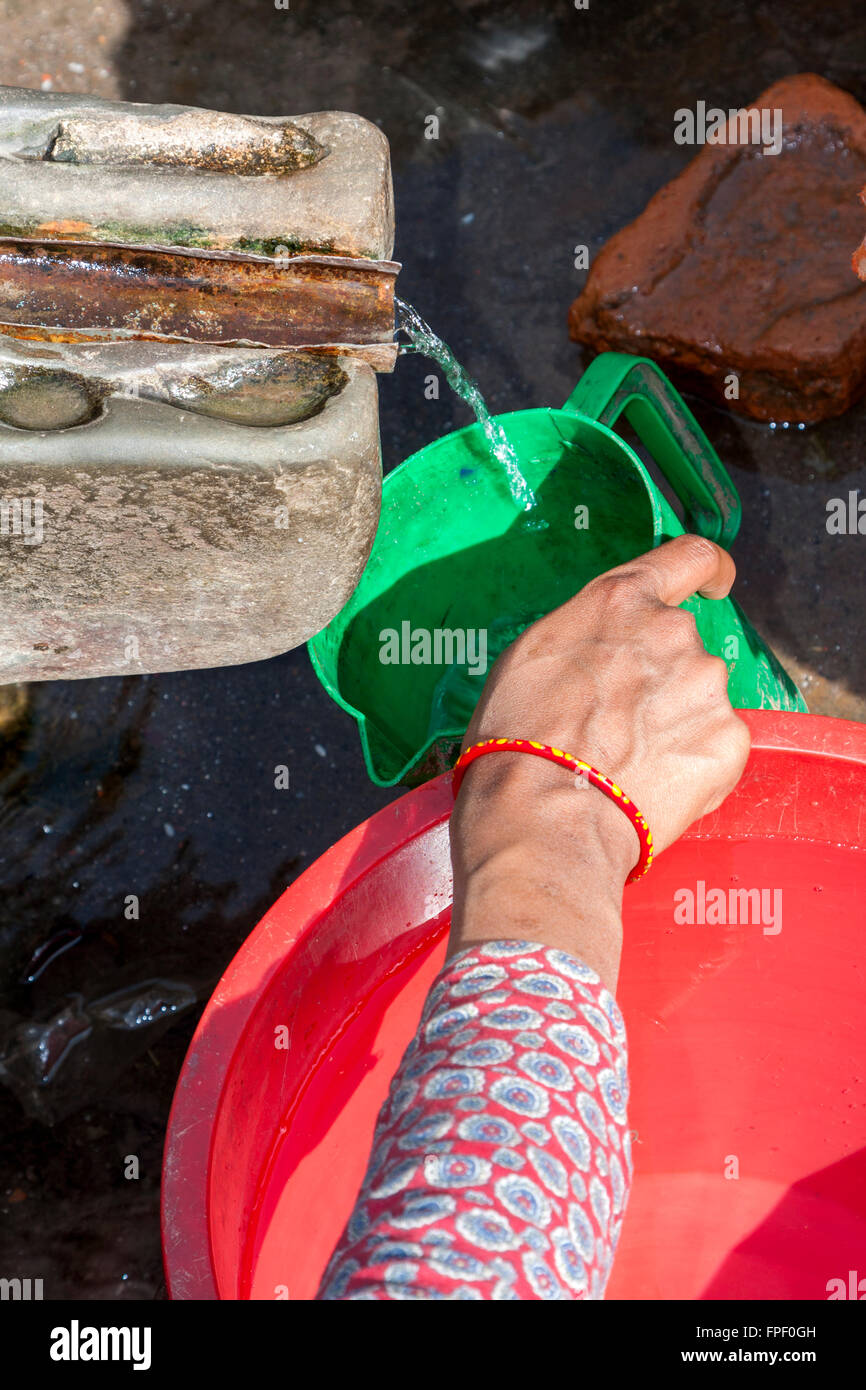 Nepal, Patan.  Frau, Füllung Kunststoff Krug an einem öffentlichen Brunnen. Stockfoto