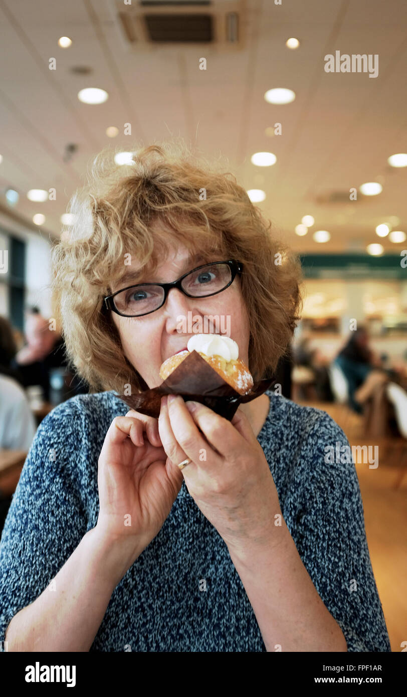 Mittlere gealterte Frau genießen ein eine Tasse Biskuit und Creme in einem Café Stockfoto