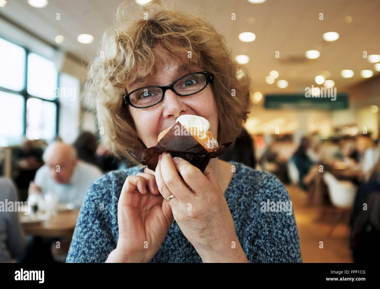 Mittlere gealterte Frau genießen ein eine Tasse Biskuit und Creme in einem Café Stockfoto