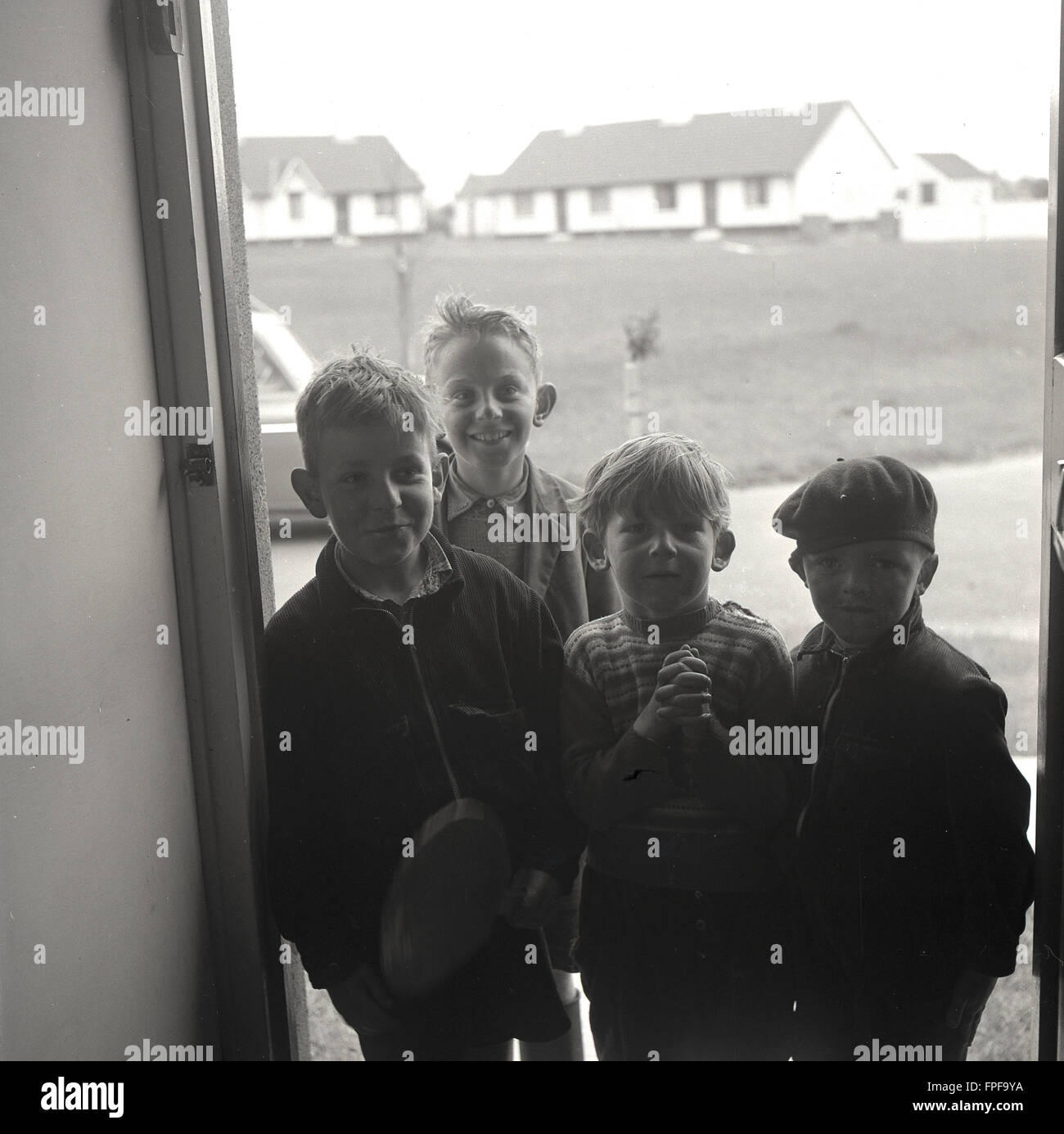 In den 1950er Jahren versammeln sich vier junge irische Jungen in einer Tür zu einem Anwesen auf einer neuen Wohnsiedlung im ländlichen Irland, um einen neuen Besucher zu treffen. Stockfoto