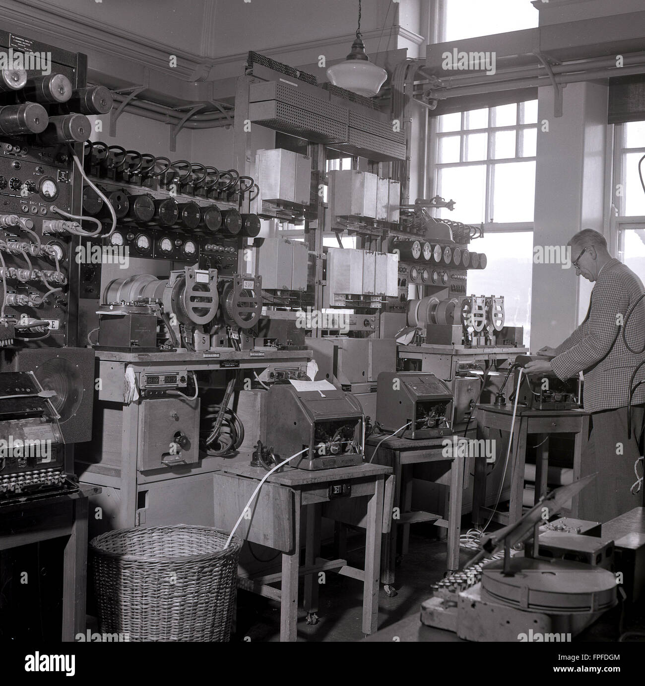 1950, historisch, ein männlicher Ingenieur, der an der Telegrafenausrüstung in einem Schaltkreis an der transatlantischen Kabelstation in Waterville, Co. Kerry, Irland, arbeitete, einst die Heimat einer der größten Kabelstationen der Welt. Die erste erfolgreiche transatlantische Telegrafennachricht wurde 1884 durch Waterville übertragen, nachdem die Commerical Cable Co zwei Kabel über den Atlantik verlegt hatte, die Kanada, Großbritannien und Frankreich über Waterville, insgesamt 2,399 Meilen Kabel, miteinander verbinden. Stockfoto
