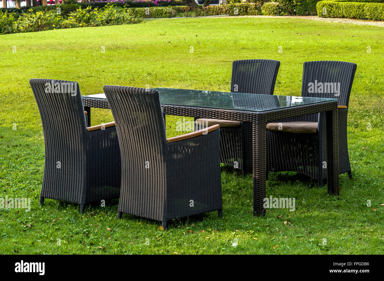 Rattan-Möbel, Tisch, Stühle und Kissen im Freien im Garten Stockfoto