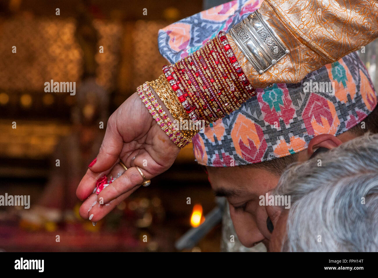 Nepal, Patan.  Armbänder auf Braut Arm präsentiert Angebot von Reis, Blütenblätter während der Trauung in den goldenen Tempel. Stockfoto