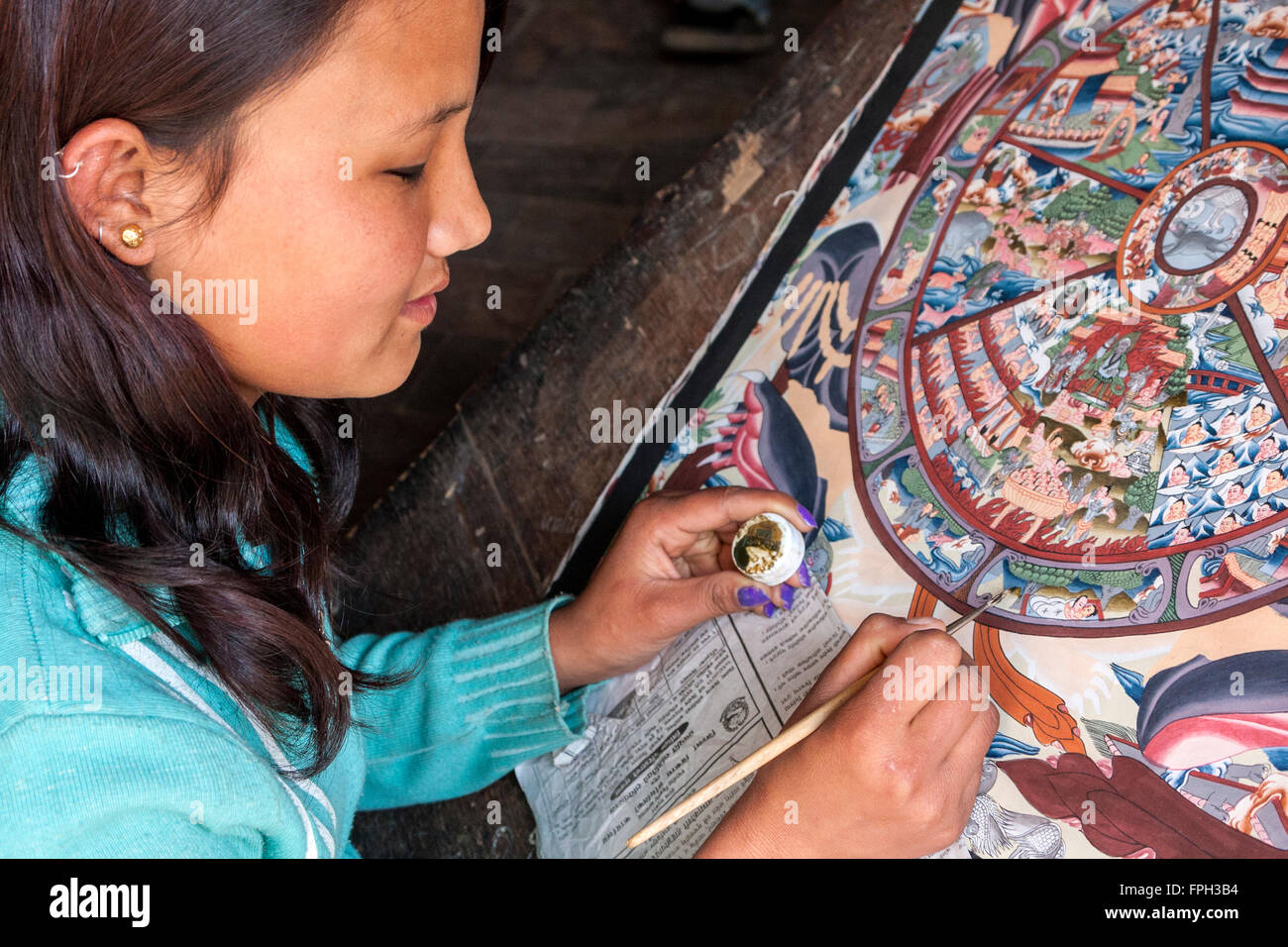 Nepal, Patan.  Junge Frau ein Thangka Malerei ein tibetisch-buddhistische Gemälde. Stockfoto