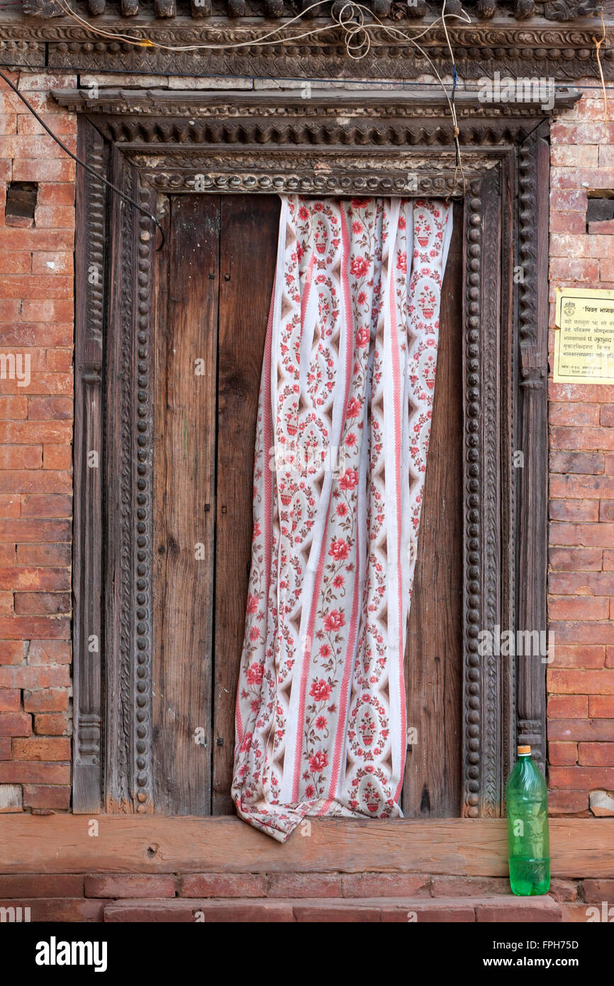 Nepal, Patan.  Vorhang-Tür des Hauses teilweise überdeckt. Stockfoto