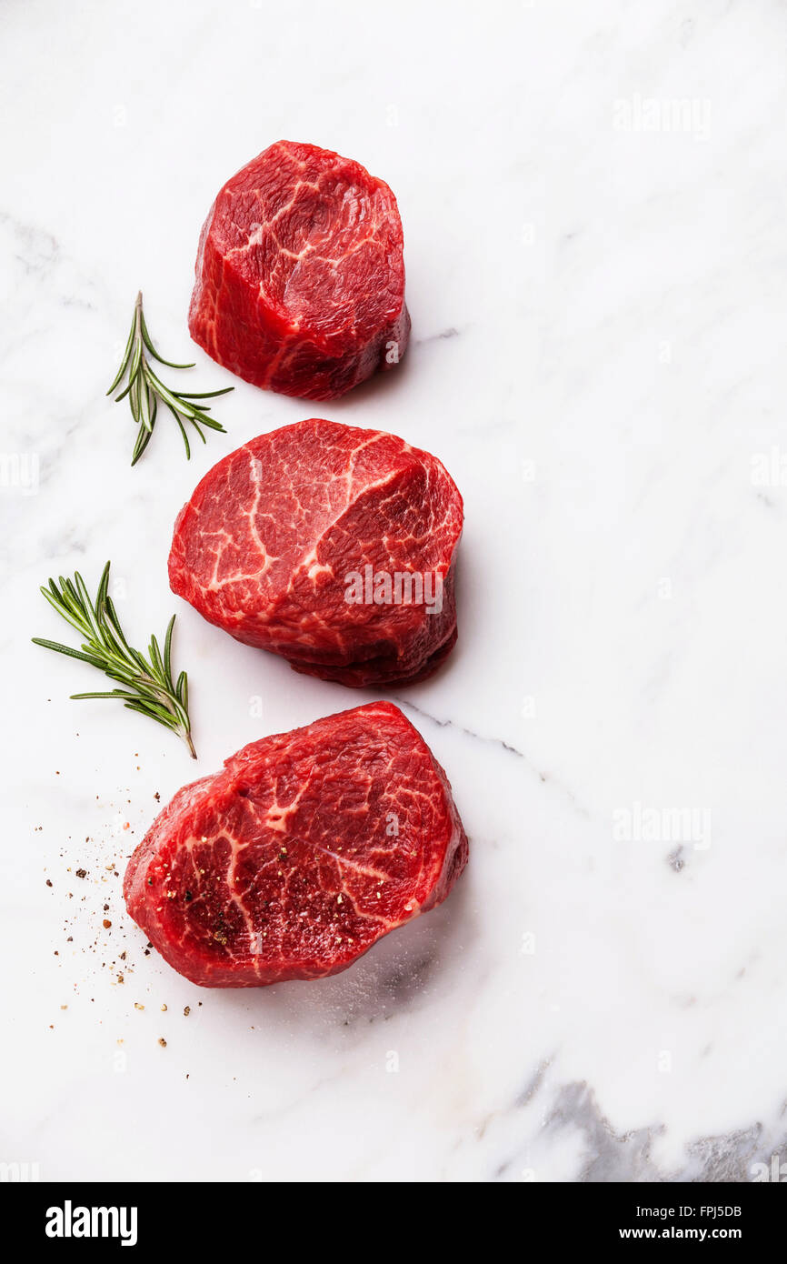 Rohes Frischfleisch marmoriertes Steak Filet Mignon und Rosmarin Kräuter auf weißem Marmor Hintergrund Stockfoto