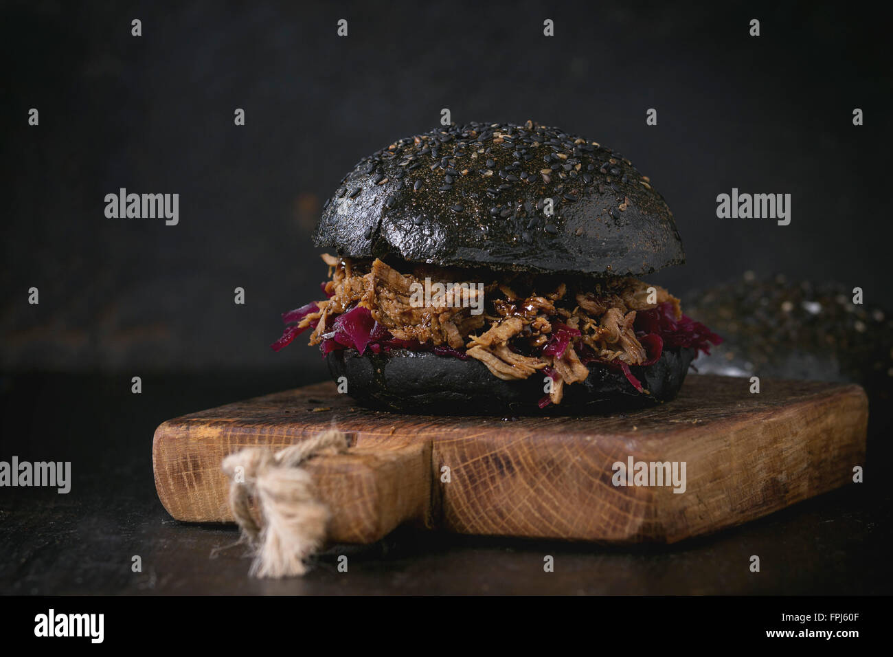 Schwarz-Burger mit Rindfleisch Eintöpfe, Rotkraut und Balsamico-Sauce, serviert auf kleines Schneidbrett aus Holz über Holztisch mit schwarz Stockfoto