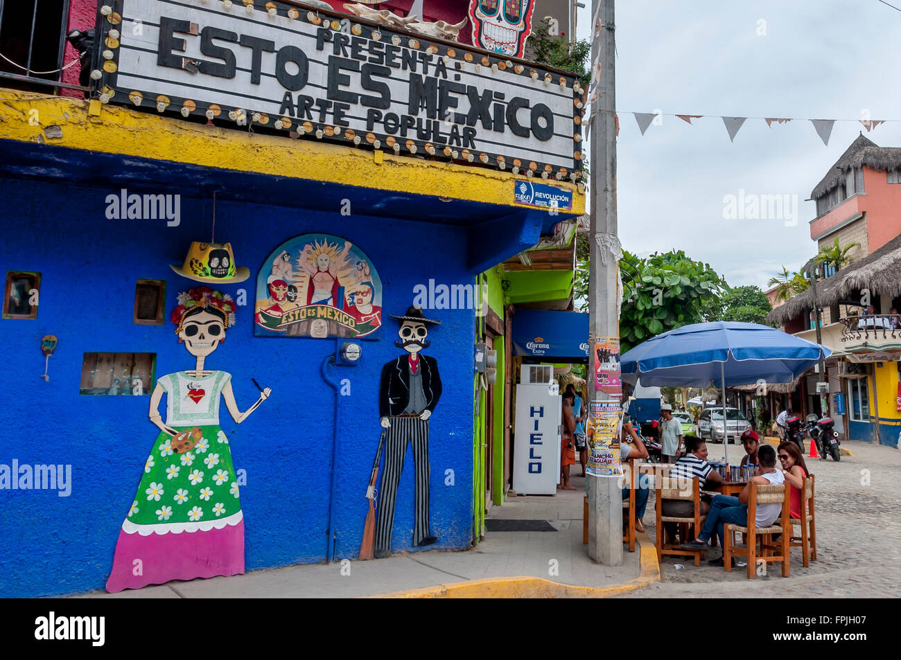 Straßenszene in Sayulita, Riviera Nayarit, Mexiko, mit 'Esto Es Mexico' Kunst und Geschenk-Shop und Besucher am Tisch draußen. Stockfoto