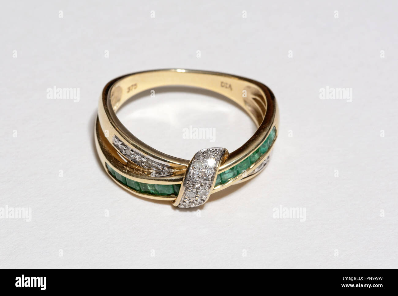 Diamant und Smaragd gelb gold Ring gegen einen einfarbigen Hintergrund, England, UK. Stockfoto